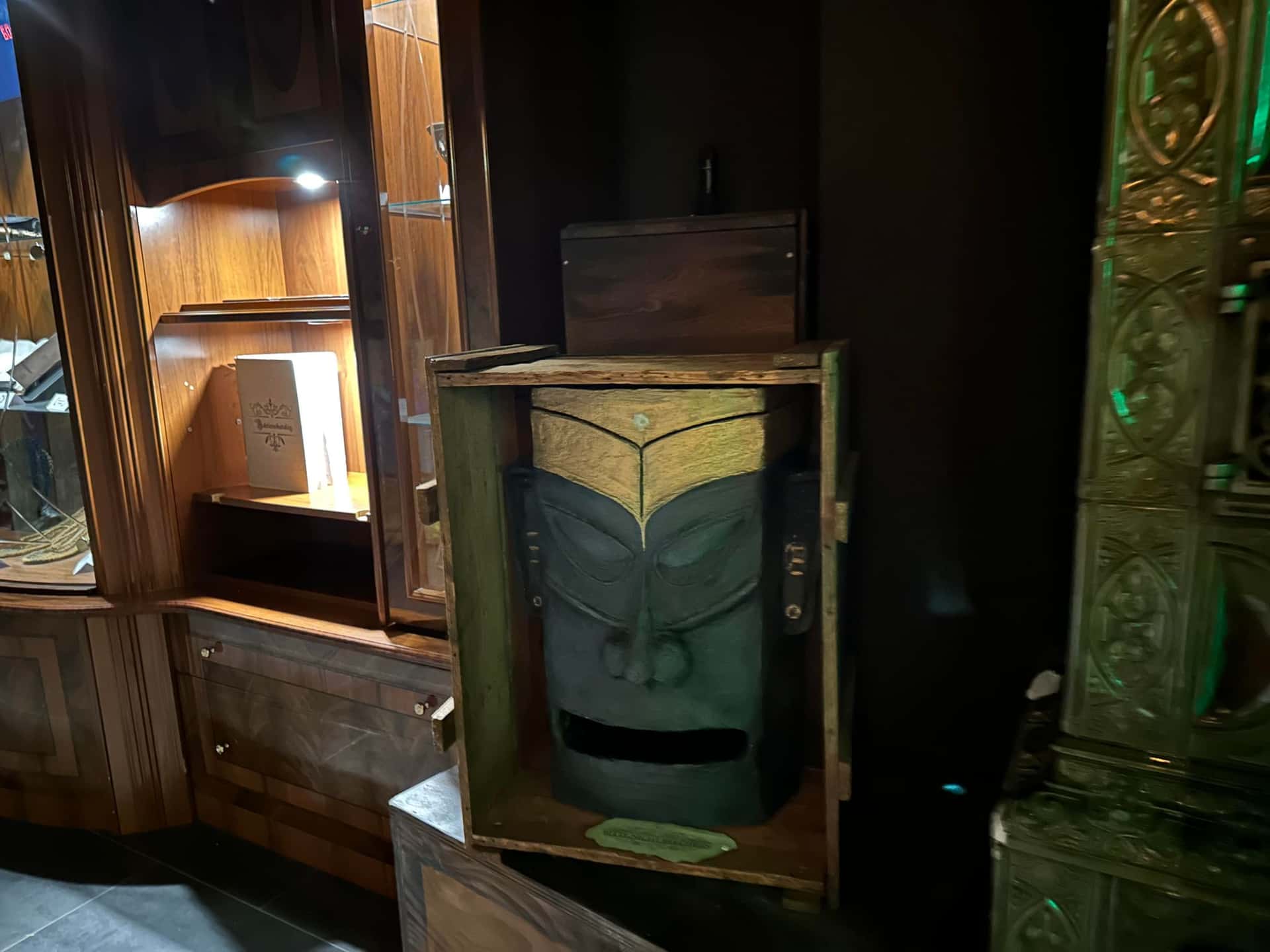 Holzkiste mit geschnitzter Totem-Maske vor Vitrinen im Escape Room Artefakt in Rosenheim
