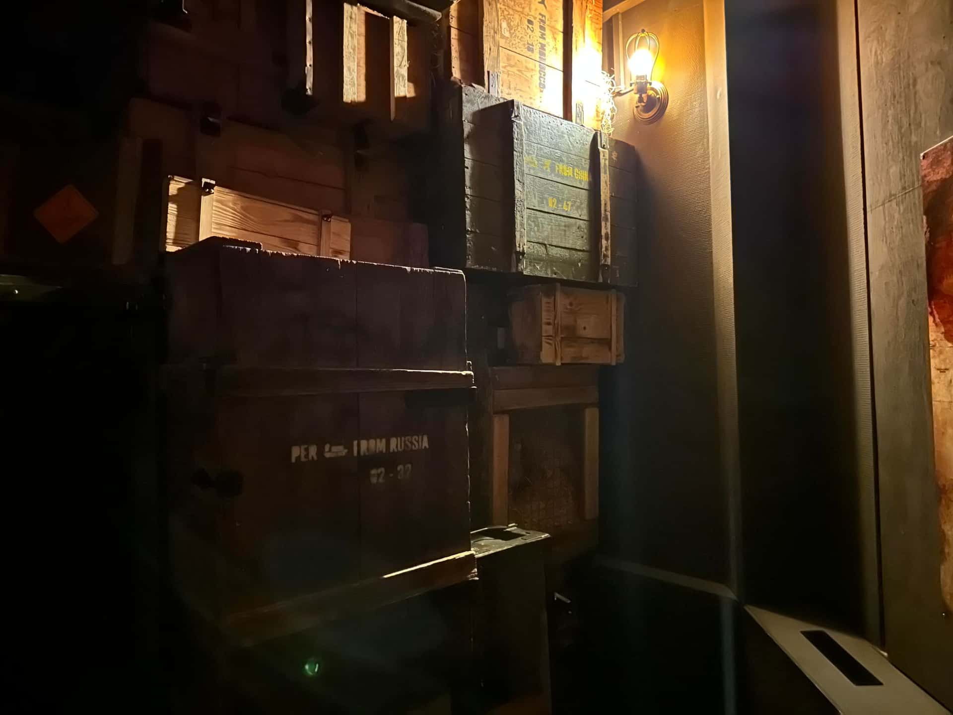 Gestapelte Holzkisten mit Wandlampe im Lagerraum im Escape Room Artefakt in Rosenheim