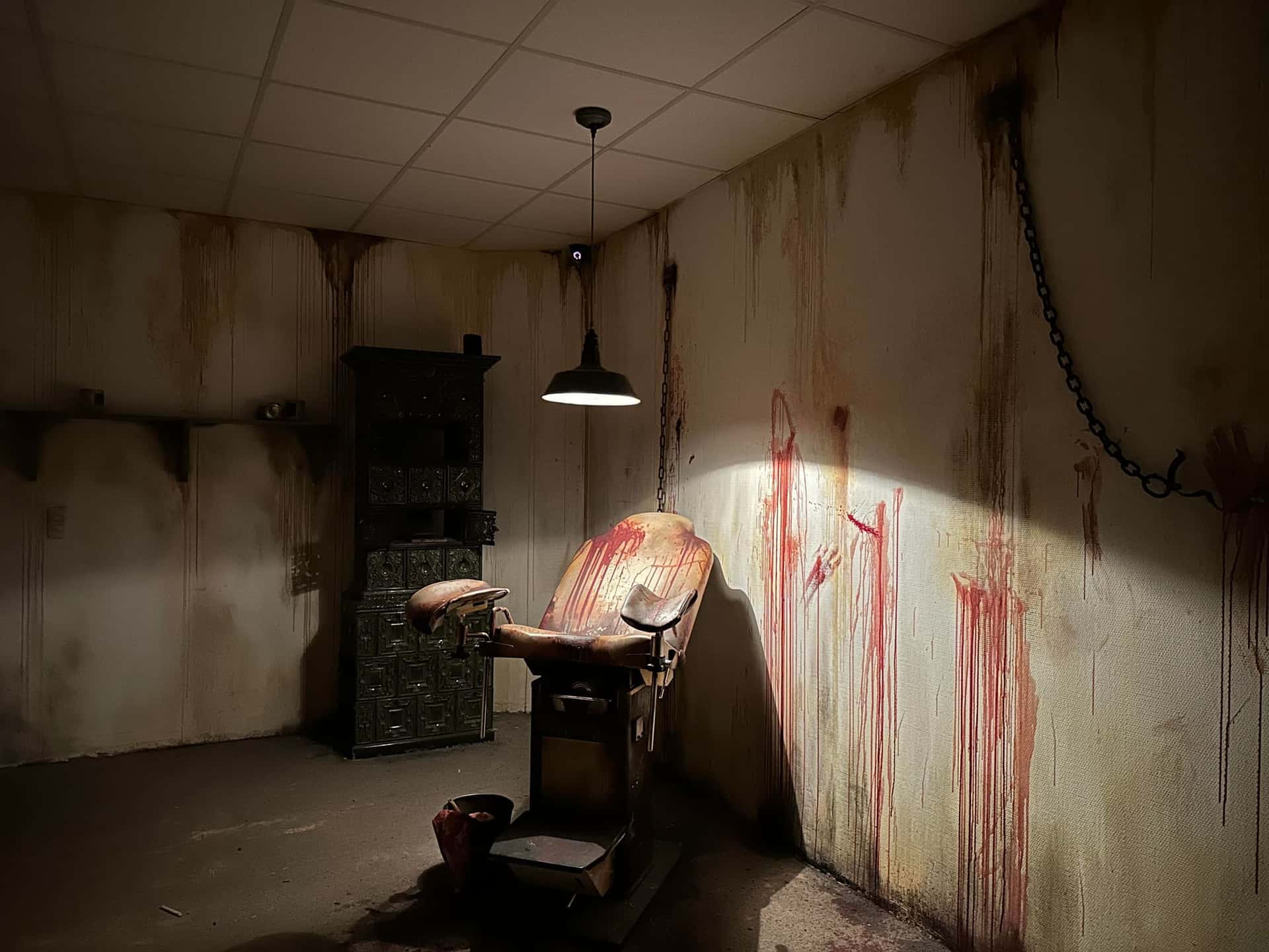 Behandlungsstuhl vor blutbespritzten Wänden im Escape Room Blutrausch in Rosenheim