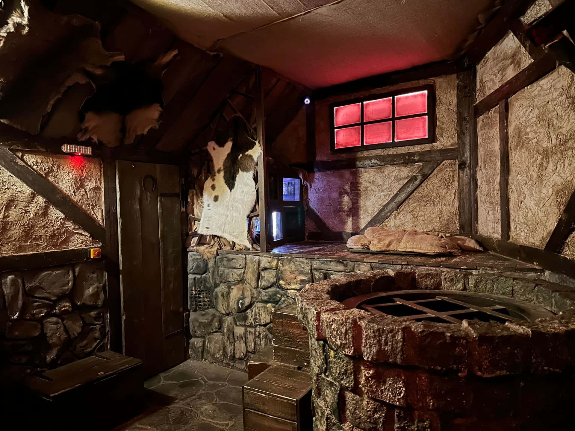 Fachwerkraum mit steinernem Brunnen und rot leuchtendem Fenster im Escape Room Der Henker in Rosenheim