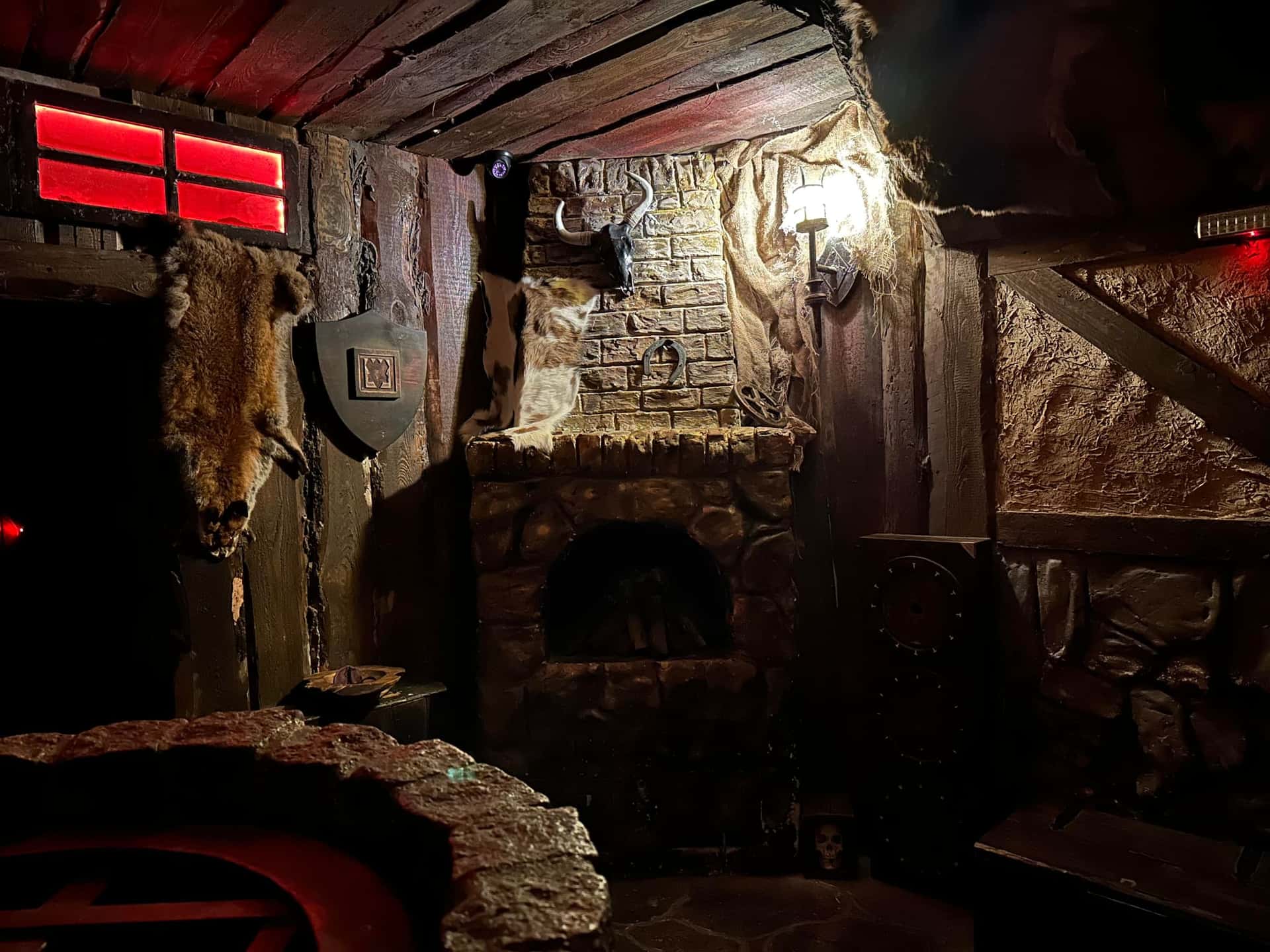 Wohnstube mit Steinofen, Fellen und Wappenschild im Escape Room Der Henker in Rosenheim
