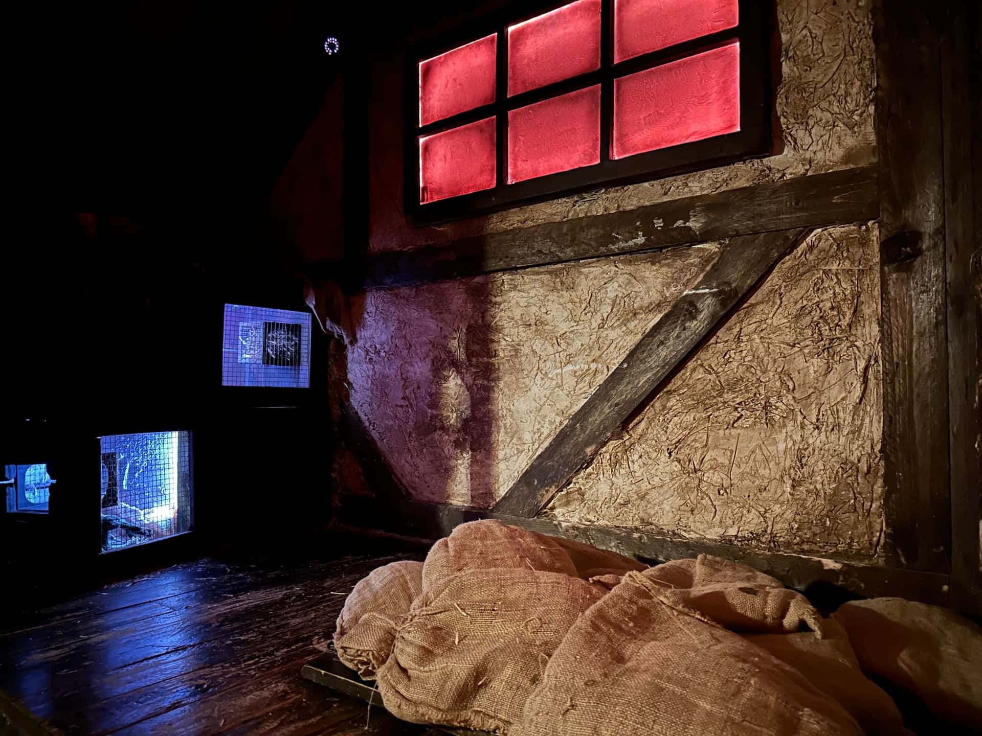 Strohsäcke auf dem Boden unter rotem Fenster im Escape Room Der Henker in Rosenheim