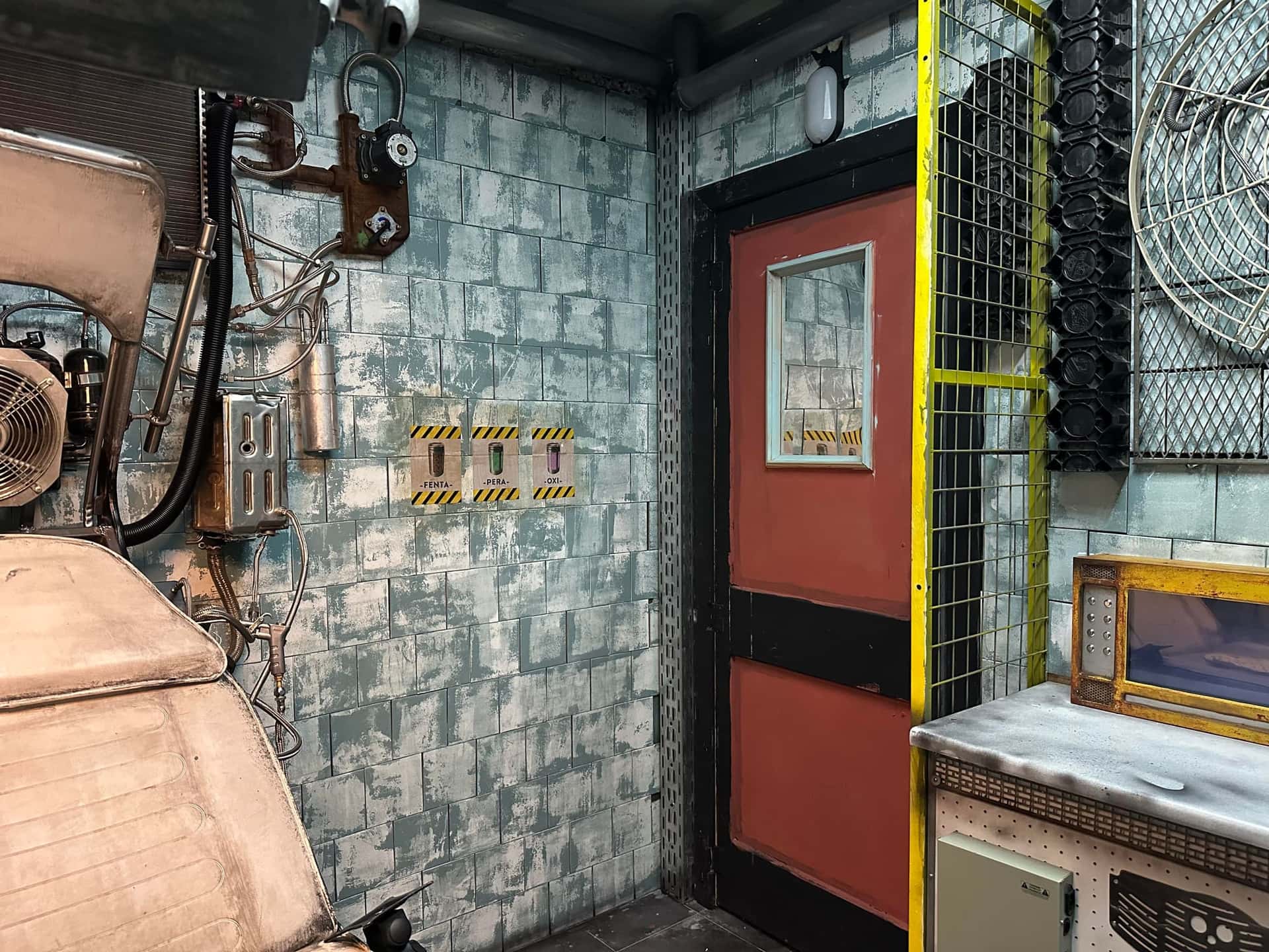 Behandlungsstuhl vor orangefarbener Tür im Escape Room Madhouse (Infection) in Rosenheim