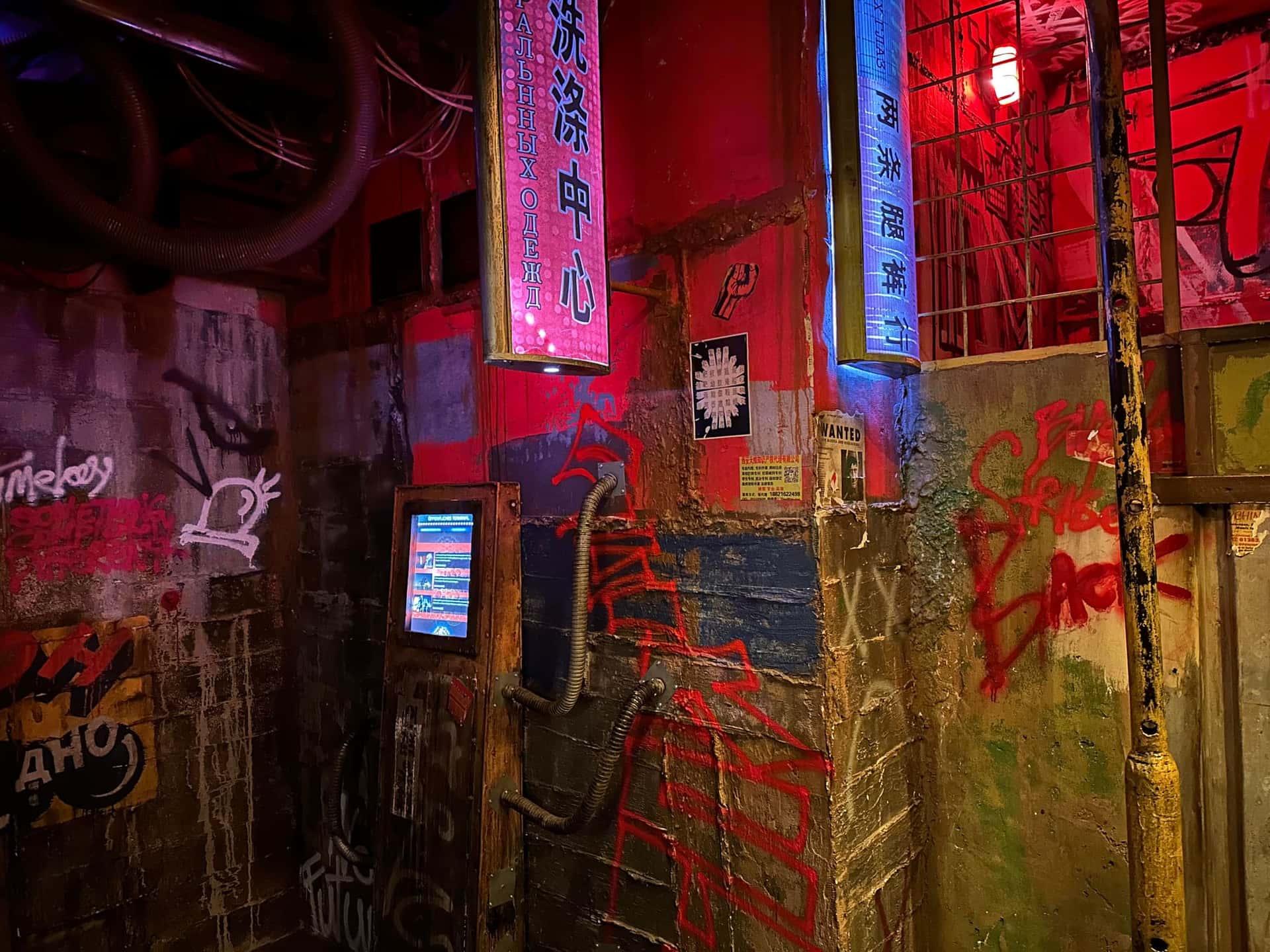 Rot beleuchtete Straßenkulisse mit Neonschildern und Terminal im Escape Room Robot Paranoia in Rosenheim