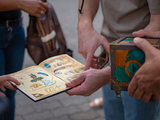 Spieler zeigen auf das Rätselbuch – Auroras Magischer Würfel, Outdoor Escape Game Rosenheim