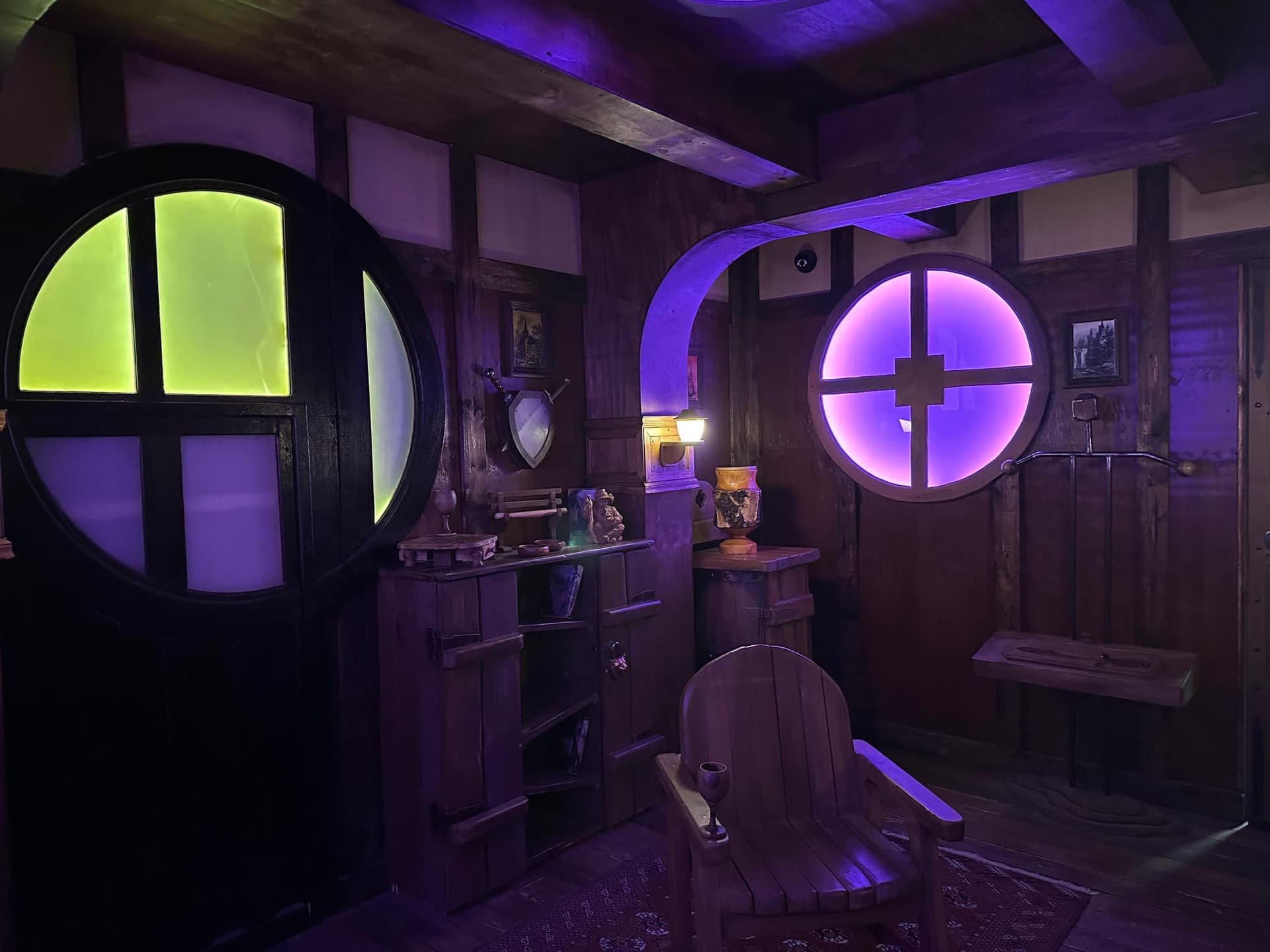 Zwei runde Fenster in Grün und Violett über einer Kommode im Escape Room Die Abenteuer des Halbling in Rosenheim