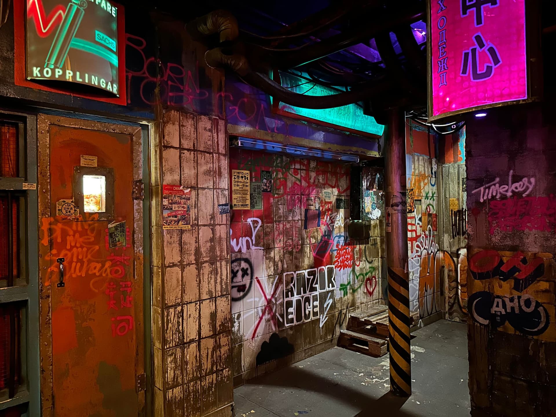 Futuristische Gasse mit Neonreklame und Stahltür im Escape Room Robot Paranoia in Rosenheim
