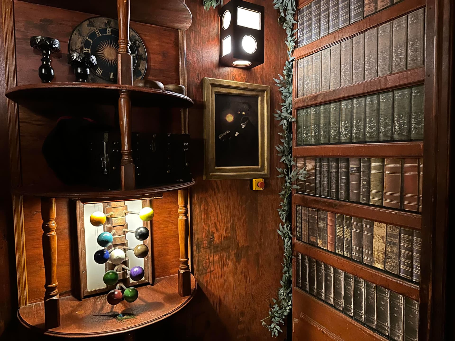 Rundregal mit bunten Kugeln neben einer Bücherwand im Escape Room Die Zauberschule in Rosenheim